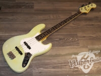 Pale yellow electric bass guitar with a white pickguard on a wooden floor, watermark reads 'Premium Vintage HyperGuitars'.